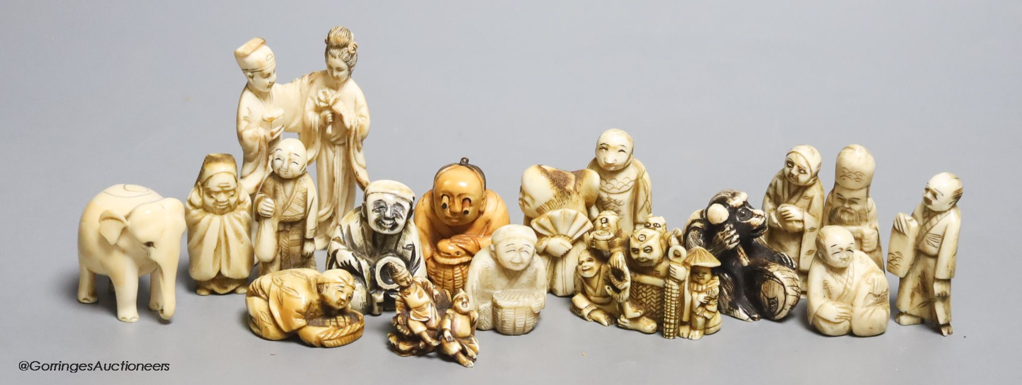 Fourteen Japanese ivory netsuke, a Chinese ivory group and elephant figure, all early 20th century